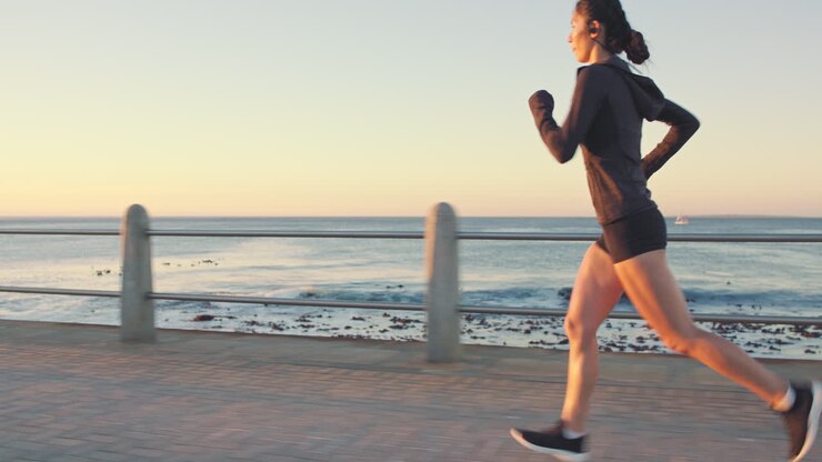Running, workout and woman on beach with focus