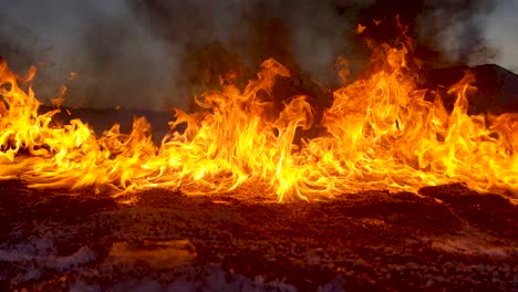 Eine-Feuerwand-Brennt-Auf-Dem-Boden,-Während-Auf-Dem-Feld-Eine-Ölpest-Beseitigt-Wird