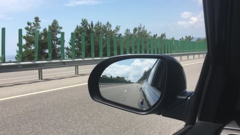 car rides on the road, a view of the side rearview mirror, reflection in the mirror. view of the bay from the car. close-up.