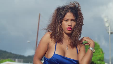 a young girl with curly hair wearing a short blue dress enjoys a tropical park on the caribbean island of trinidad