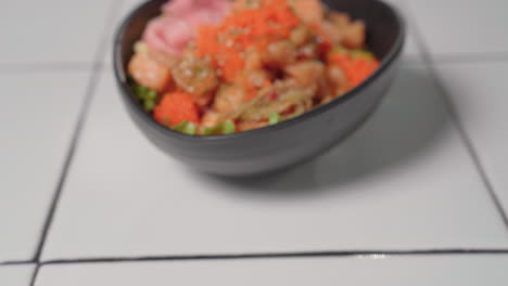 rack focus on hawaiian poke bowl with raw salmon and ahi tuna fish, topped with tobiko and sesame seeds