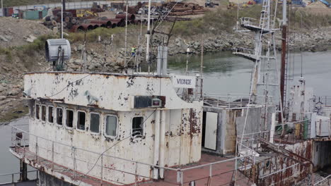 Rusty-grey-half-submerged-shipwreck-anchored-near-the-shore-on-a-cloudy-overcast-day