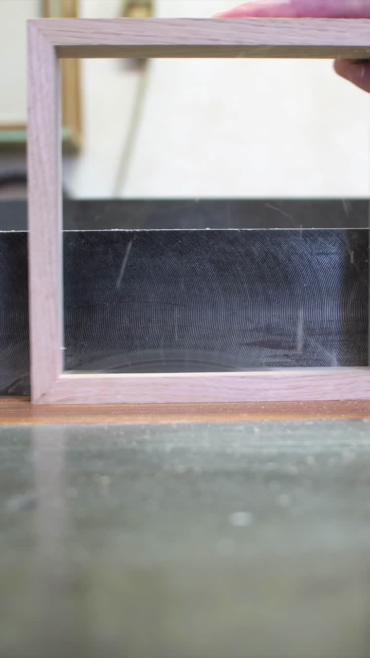 Falegname che taglia a metà una cornice di legno con una sega circolare, ripresa laterale verticale al rallentatore