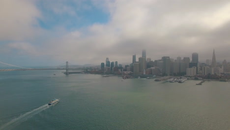 Luftaufnahme-Der-Skyline-Von-San-Francisco-Mit-Touristenboot-Und-Blauem-Himmel-4k