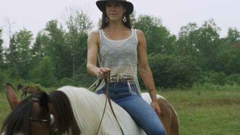 stylish confident cowgirl rides her horse bareback, walking slowly past the camera