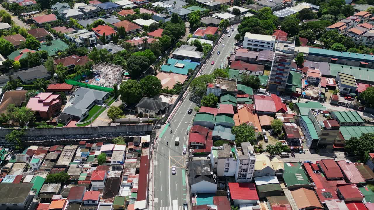 Aerial flyover of residential house rooftops along busy streets of Col. Bonny Serrano Avenue, Quezon City, Philippines