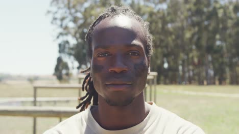 porträt eines selbstbewussten afroamerikanischen männlichen soldaten mit dreadlocks und schwarzen augen im feld