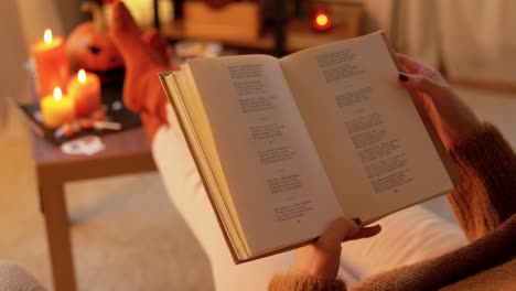 woman reading a book by the fireplace on a cozy halloween night