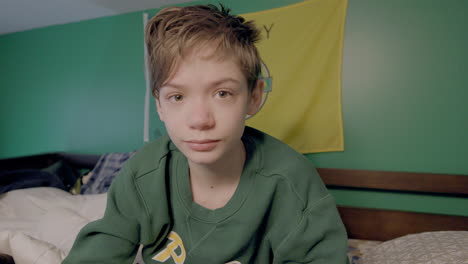 Cute-boy-in-his-bunk-bed-with-bedhead-and-sleepy-eyes-looks-at-camera