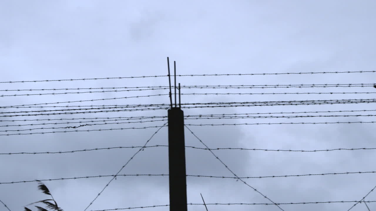 The barbwire fence of a prison camp on a gray and stormy day
