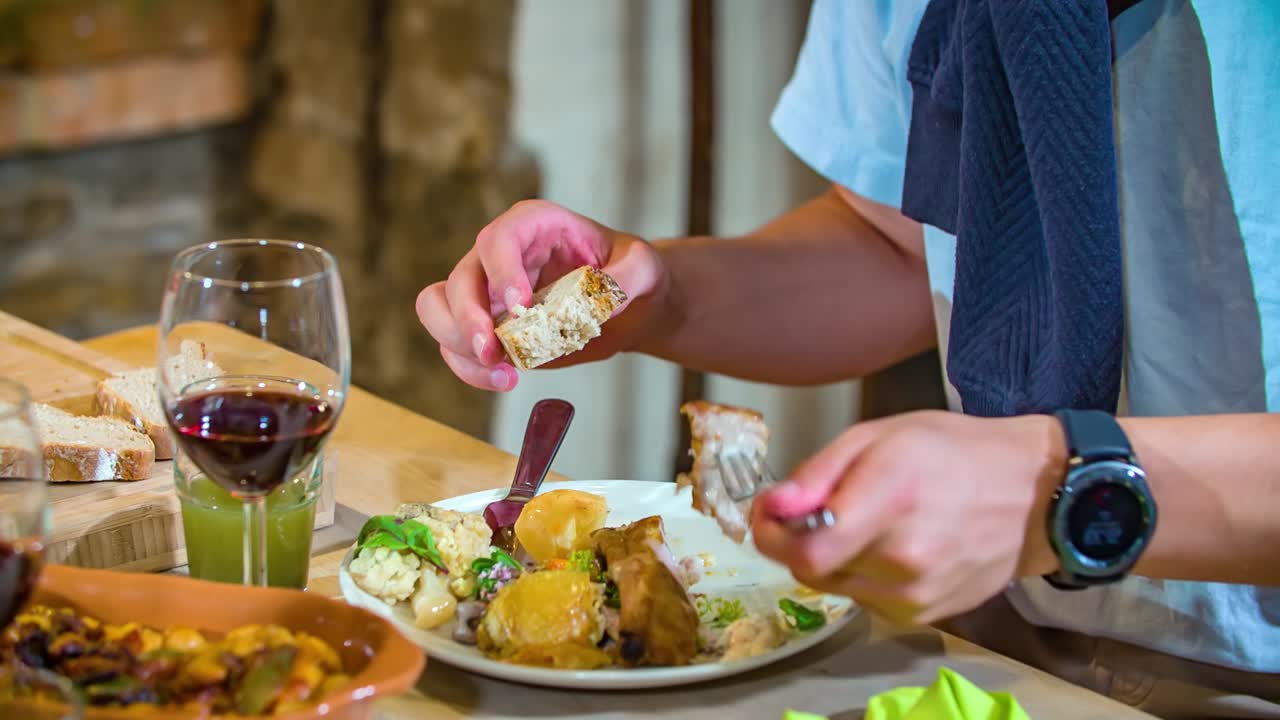 el joven disfruta de la comida de carne, verduras, pan recién horneado y vino tinto