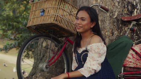 woman relaxing by a tree with a bicycle