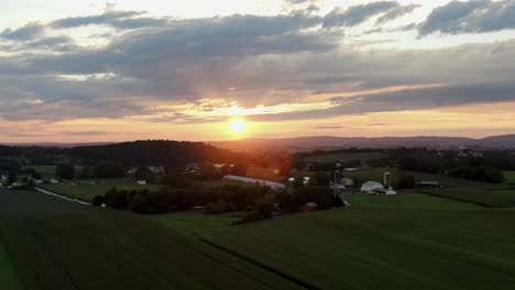 luchtfoto push-in dolly shot van zonsopgang, zonsondergang in lancaster county pennsylvania, glooiende heuvels en groene landbouwgrond in de zomer, prachtige wolken en lucht, panorama