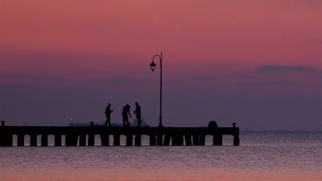 people on a pier at sunset