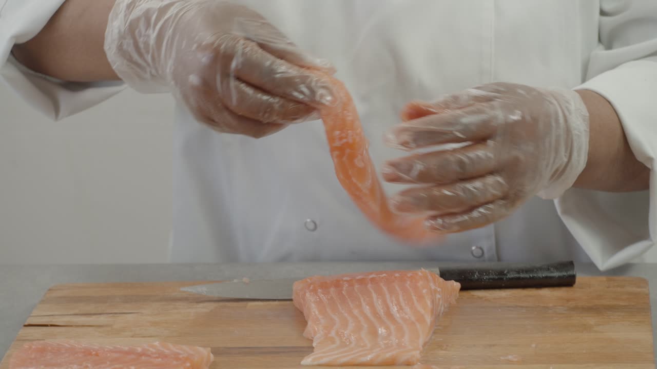 Male chef cuts fillet of fresh salmon into large chunks. Cooking fish in kitchen. Preparation of ingredients by chef to prepare dish. Cooking in the restaurant kitchen. Food ingredients for gourmets