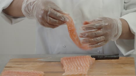 male chef cuts fillet of fresh salmon into large chunks. cooking fish in kitchen. preparation of ingredients by chef to prepare dish. cooking in the restaurant kitchen. food ingredients for gourmets