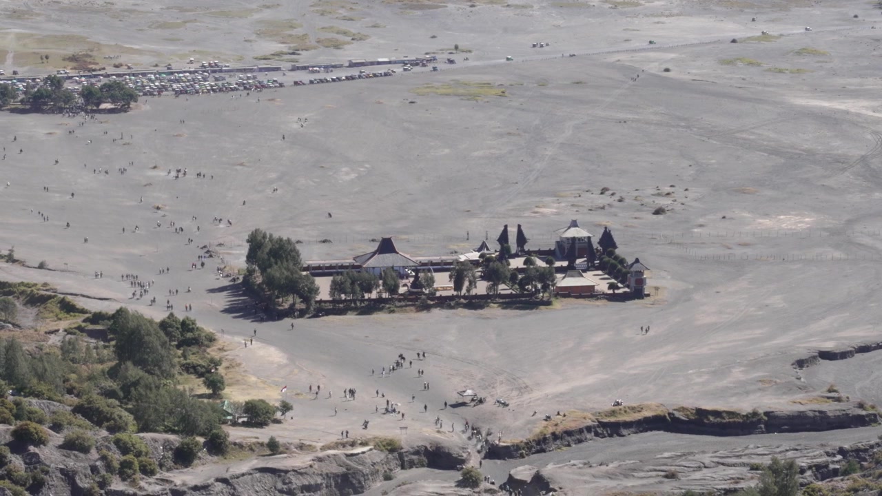 Veduta aerea del tempio Pura Luhur Poten con visitatori che attraversano una piana di sabbia vulcanica