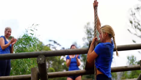 mujer en forma bajando la cuerda durante el curso de obstáculos 4k