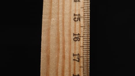 Wooden-ruler-marked-with-digits-turning-on-black-background