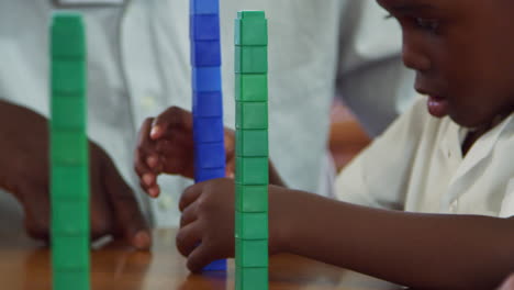 teacher helping elementary school boy balancing blocks