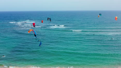 Filmische-Drohnenaufnahme-Von-Professionellen-Kitern,-Die-Auf-Einer-Tropischen-Insel-Surfen