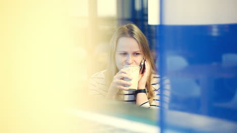 mujer en el café teniendo una conversación telefónica mientras bebe té