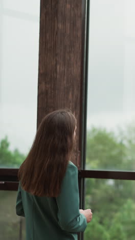 woman in charge stares out office window . series of negative reviews from influential stakeholders rattles confidence in woman reputation and future prospects