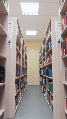 bookshelves in the university library. shot between two shelves filled with books. vertical video