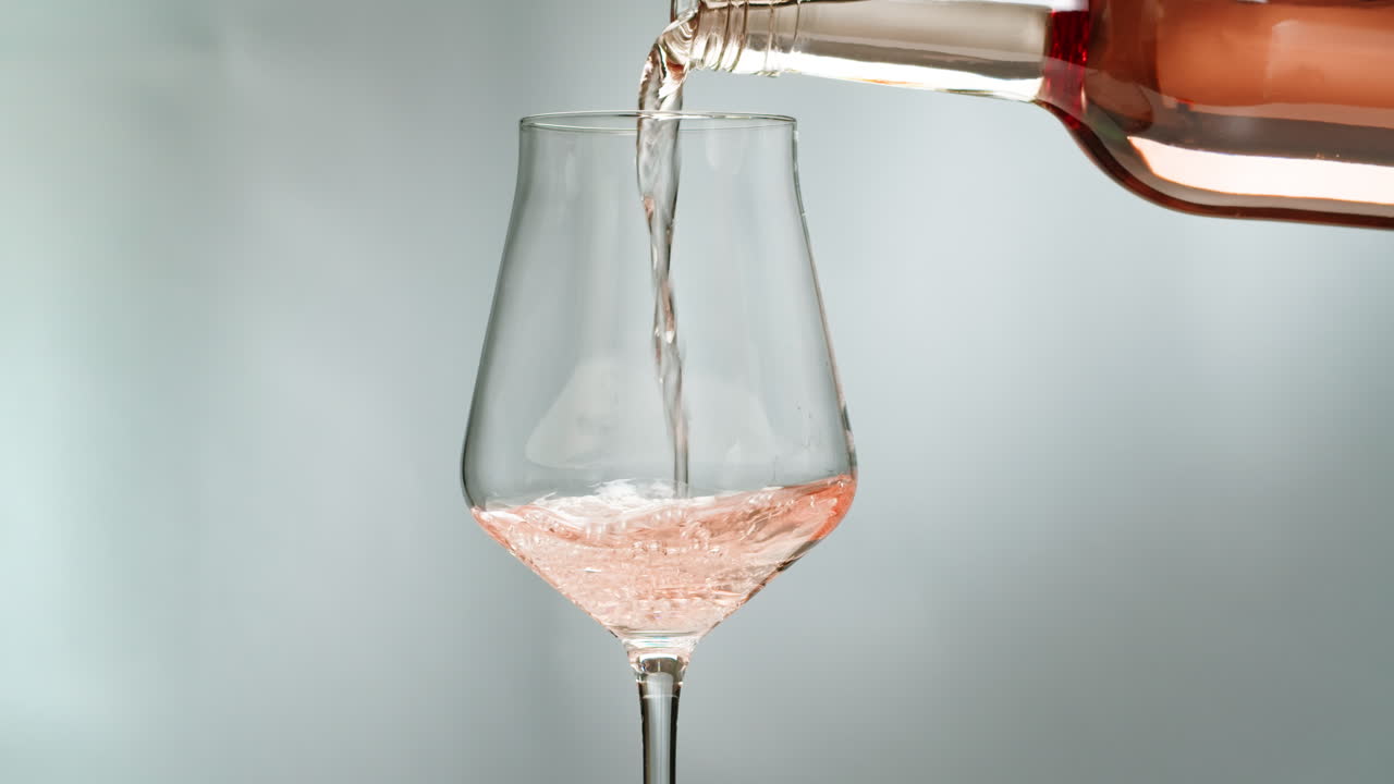 Orange or white wine bottle and glass against a sunset in a peaceful vineyard, pouring of ecological natural wine.