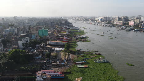 aerial: ship wrecking dockyard at buriganga river bank with cityscape - drone flying forward shot