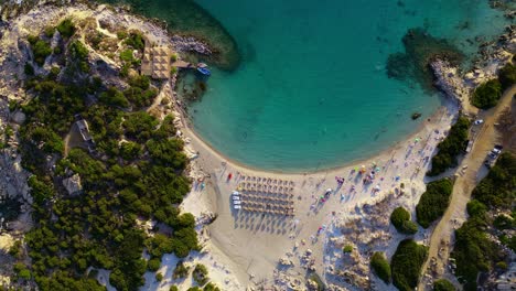 Descending-over-Punta-Molentis-Beach-full-of-people-enjoying-a-sunny-day