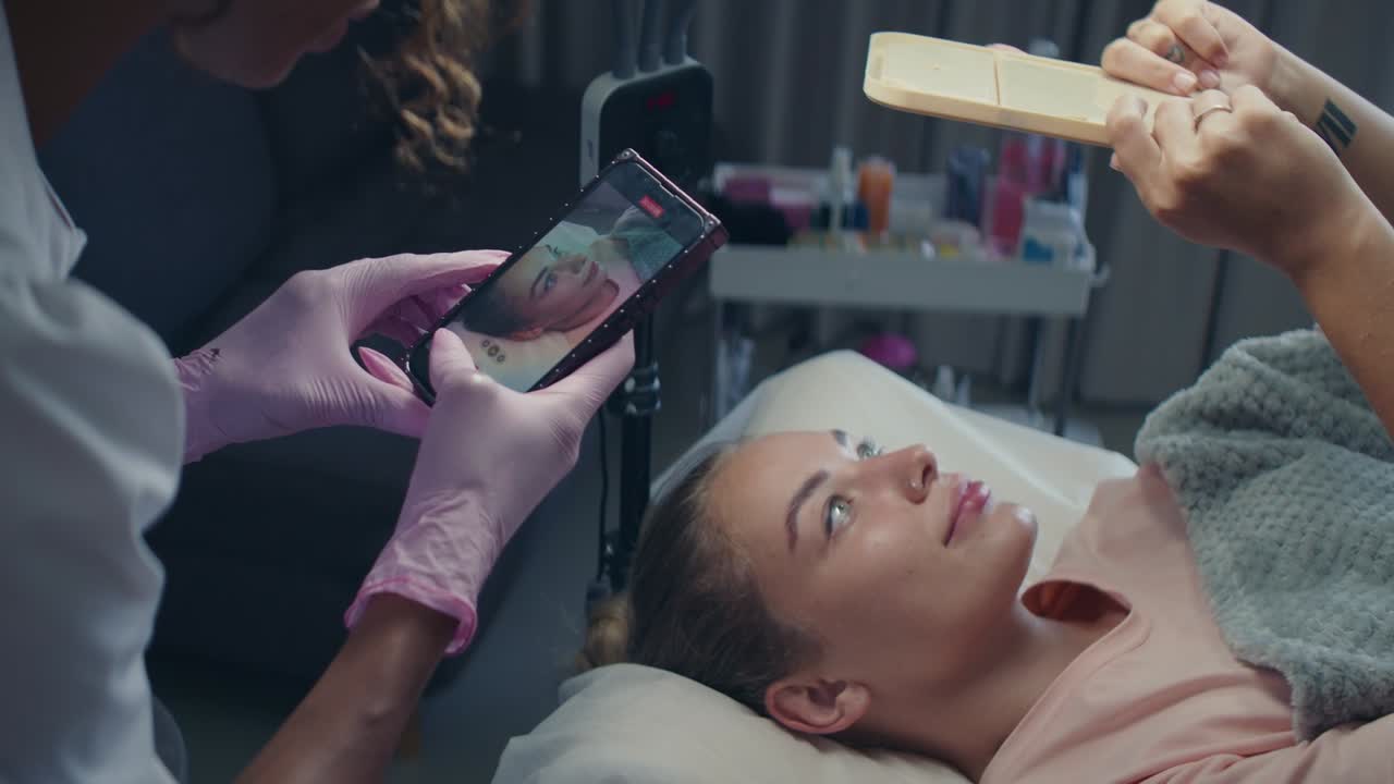 Woman getting a facial treatment with mobile phone consultation
