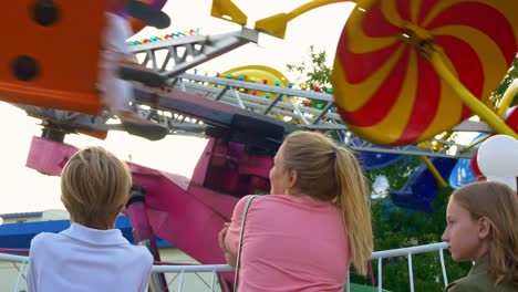 a mother with children in an amusement park, standing by a carousel that spins very quickly, the children are delighted with the fast carousel. cheerful childhood at the sunday fair