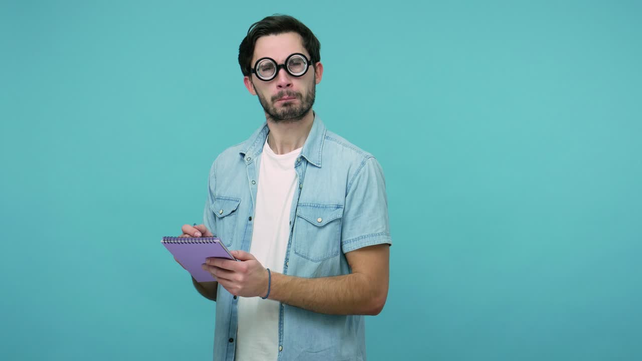 gracioso geek raro con gafas estudiando. tipo barbudo inteligente con gafas dióptricas redondas haciendo notas en papel