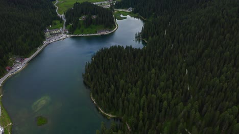 aerial overhead flying over scenic lake misurina with forest pine trees around it