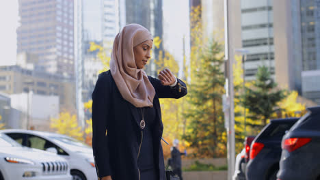 Side view of young Asian woman in hijab using mobile phone in the city 4k