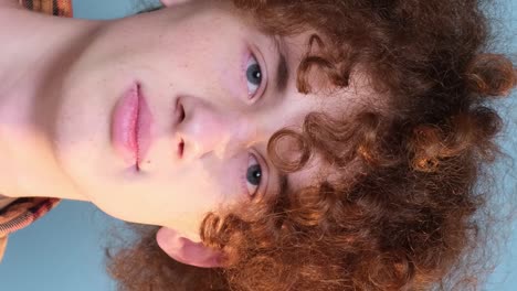 a guy with curly hair is looking at the camera on a blue background in the studio a guy with curly hair is looking at the camera on a blue background in the studio