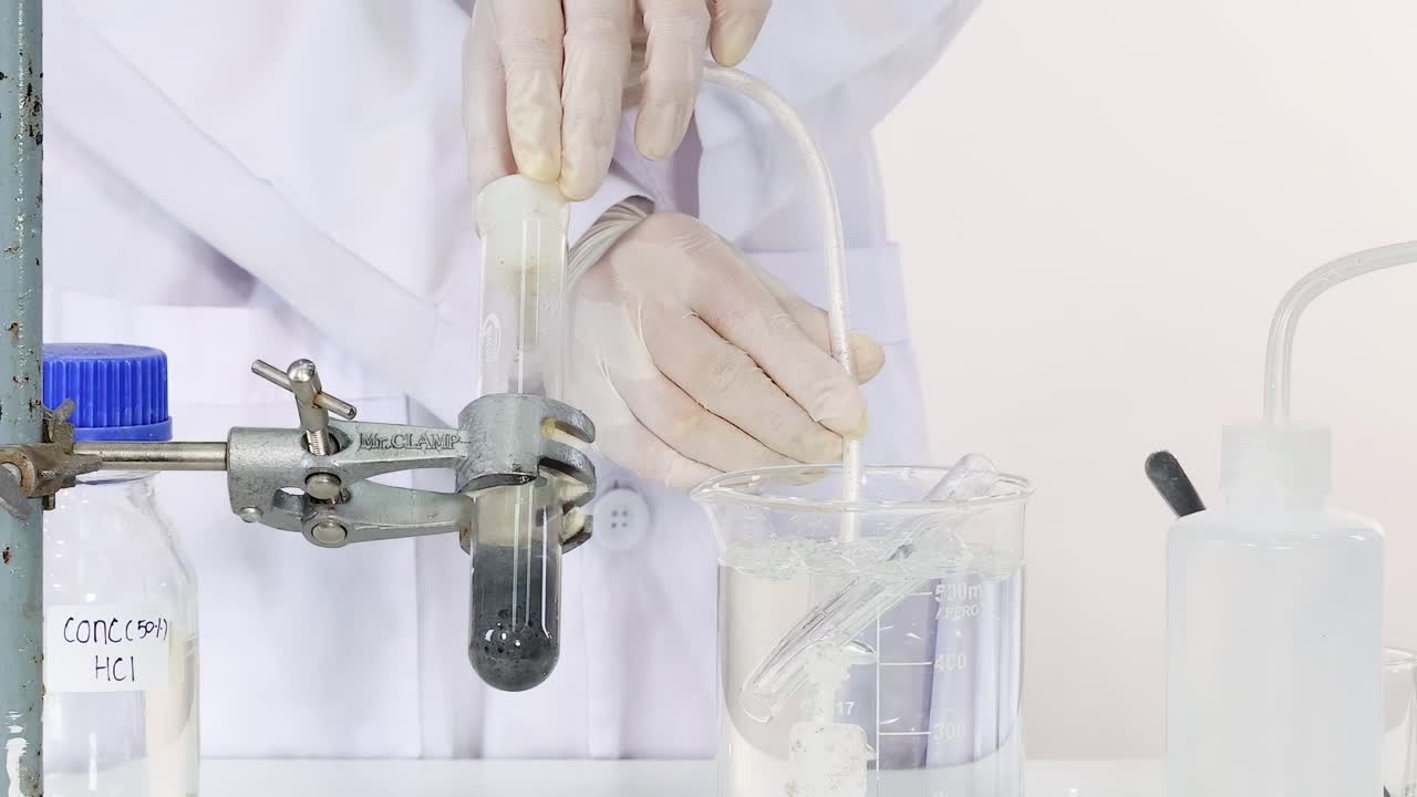 Demonstrating the setup of a chemical reaction using concentrated HCl and laboratory apparatus.