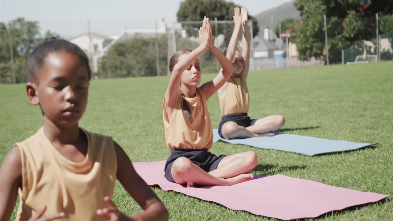 estudiantes de escuelas primarias diversas practicando yoga en el estadio en cámara lenta