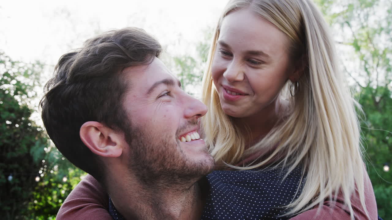 Portrait Of Couple With Man Giving Woman Piggyback At Home In Back garden