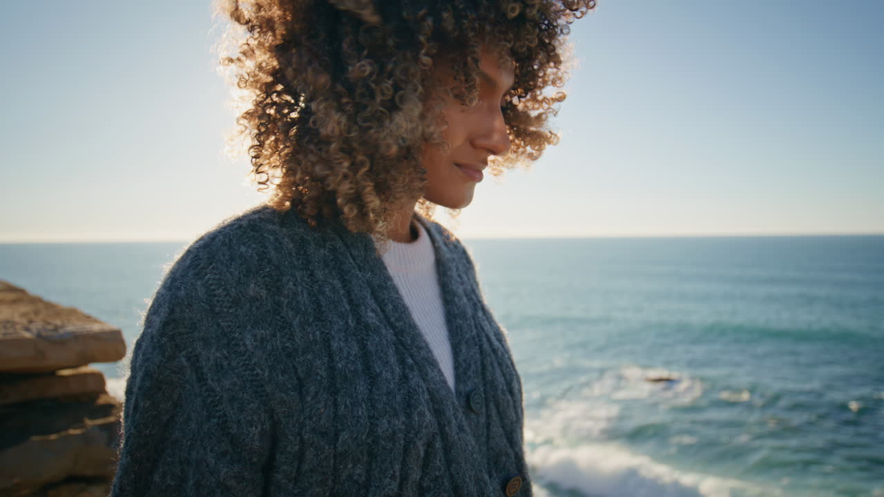 Relaxed lady enjoying sea breeze at rocky coast closeup. Woman touching hair