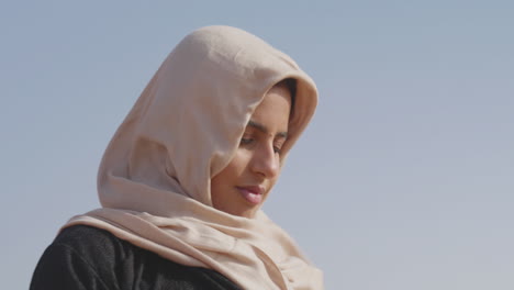 ritratto di una donna musulmana in hijab che balla e muove dolcemente le mani in un deserto ventoso 1