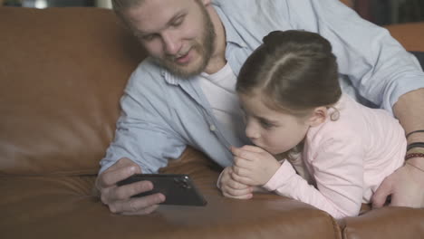 Hombre-E-Hija-Viendo-Un-Teléfono-Inteligente-En-Casa