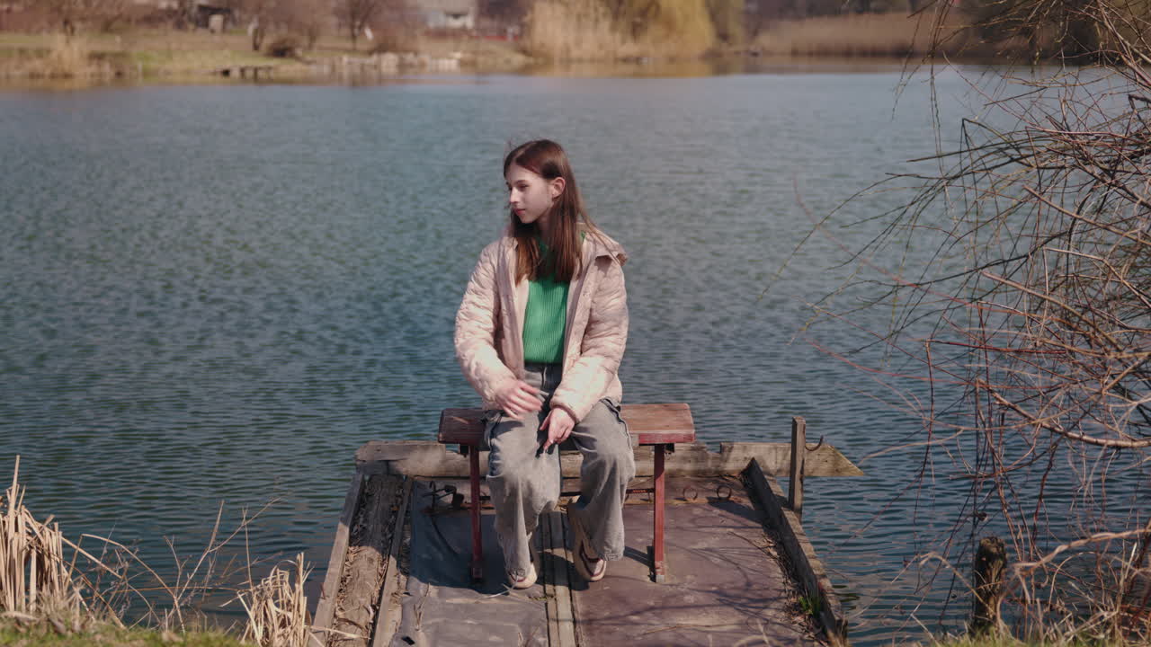 Teenage Girl Sitting on a Dock by a Lake
