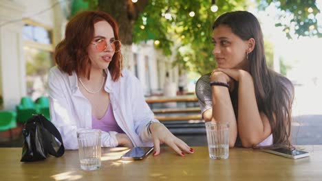 two women friends having a conversation in an outdoor cafe