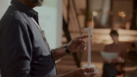 environmental engineer holding wind turbine model and explaining presentation