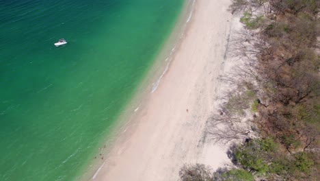 drone aéreo panorámico filmado sobre un océano tranquilo y claro junto a playa conchal