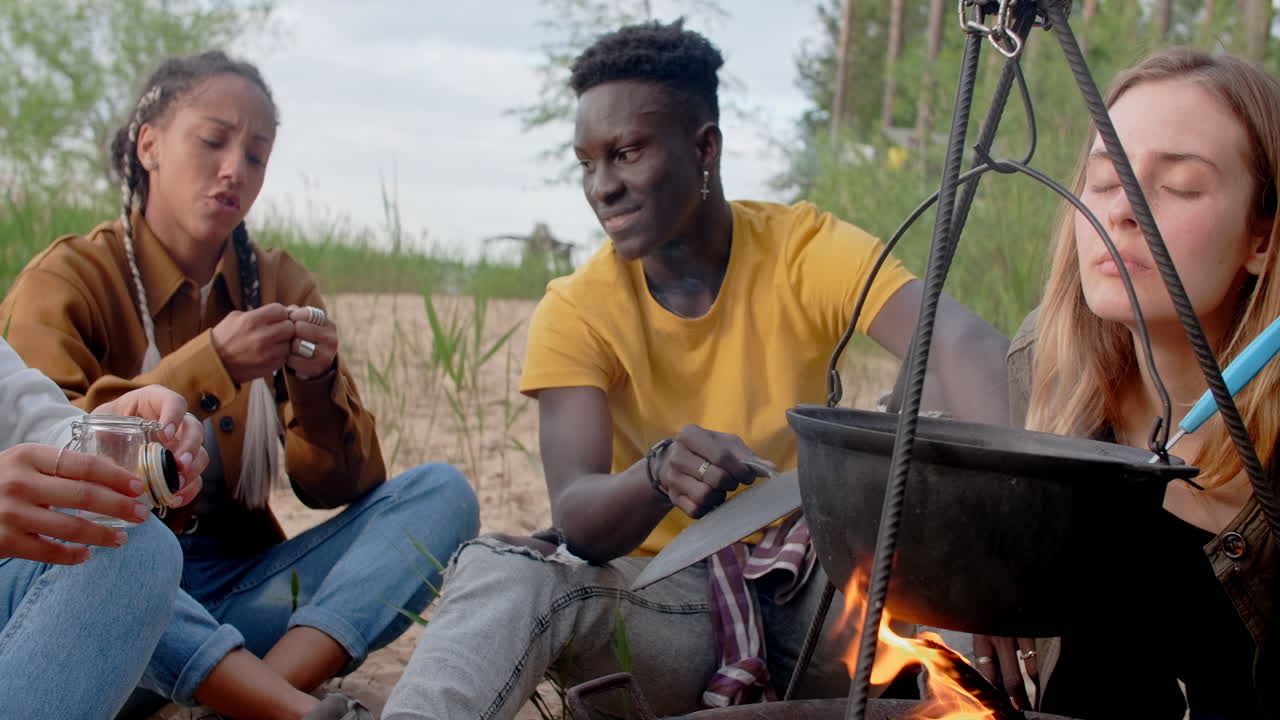 Friends Cooking Together Around a Campfire