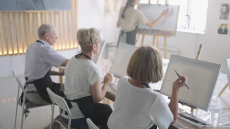 slow motion old people attend drawing courses. the teacher helps pensioners who attend drawing courses to draw. a group of retired friends at a drawing lesson