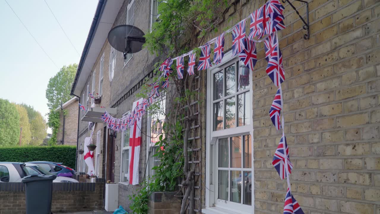 England flag and small union jacks are hanging outside of the house commemorating VE Day also known as Victory in Europe during a windy day